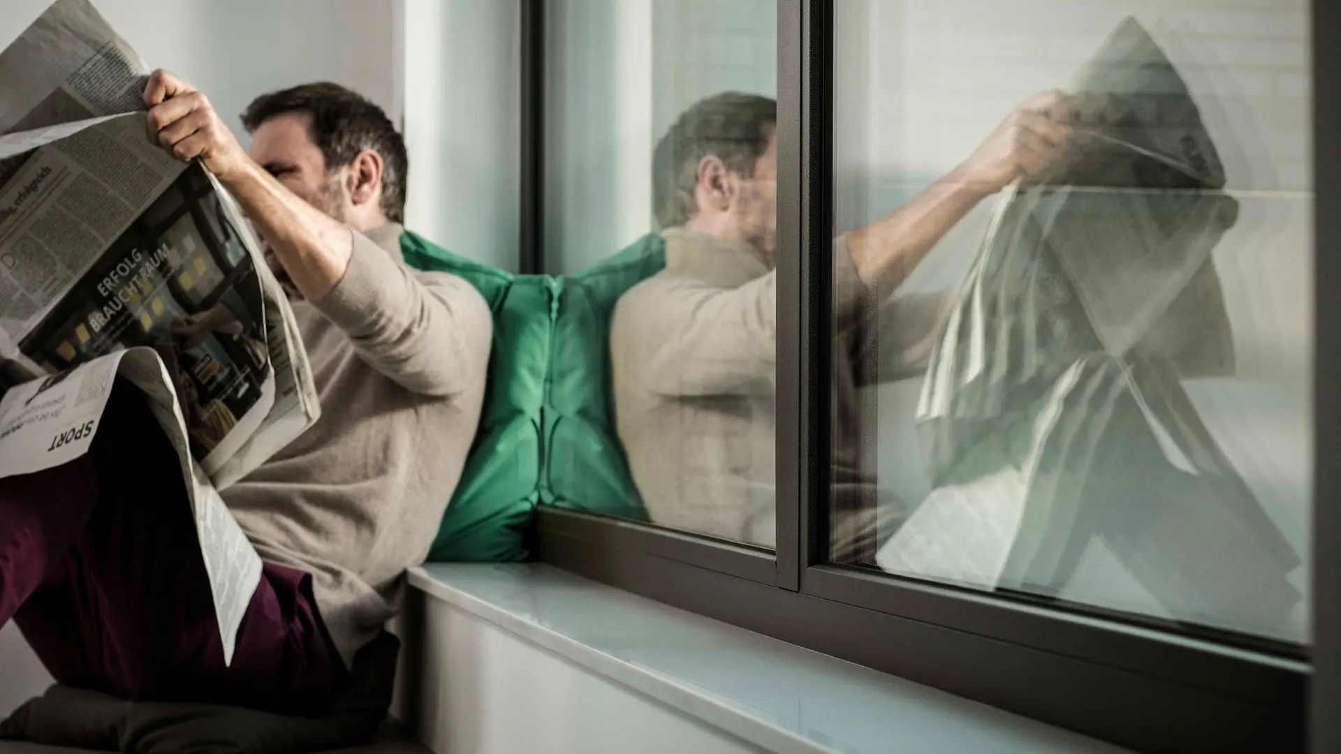Mann liest an einem großen Fenster