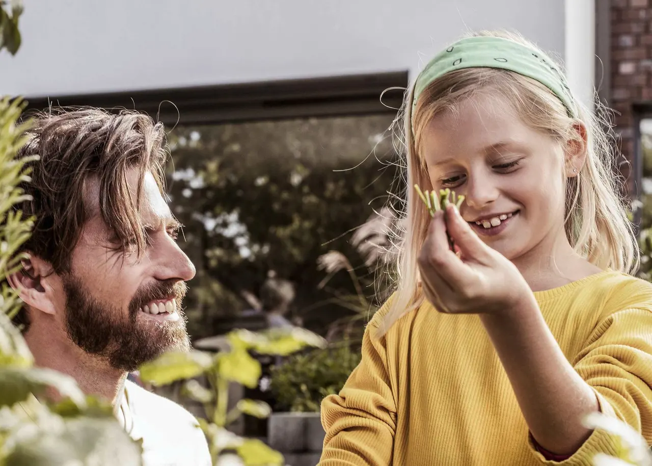 Vater und Tochter betrachten ein Blatt im Garten